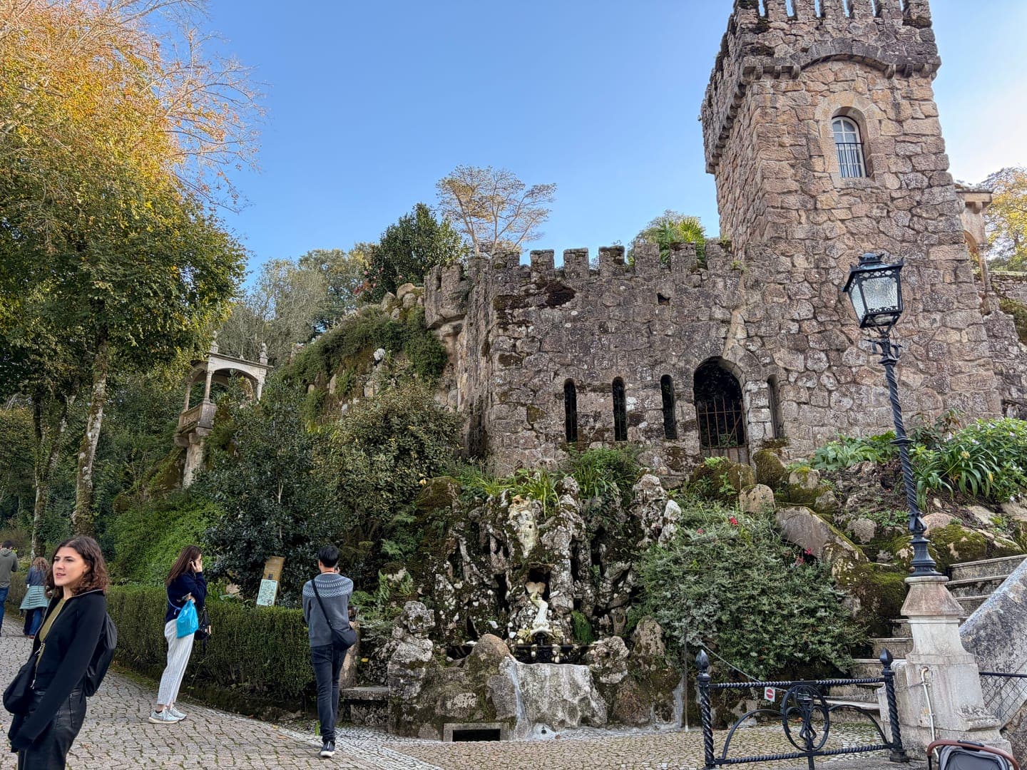 Exploring the enchanting Quinta da Regaleira in Sintra, Portugal, where every corner reveals a new architectural wonder. This shot captures the intricate stonework of one of the estate's many grottoes and towers, nestled amidst lush greenery. The blend of natural beauty and man-made artistry creates a truly magical and mysterious atmosphere.