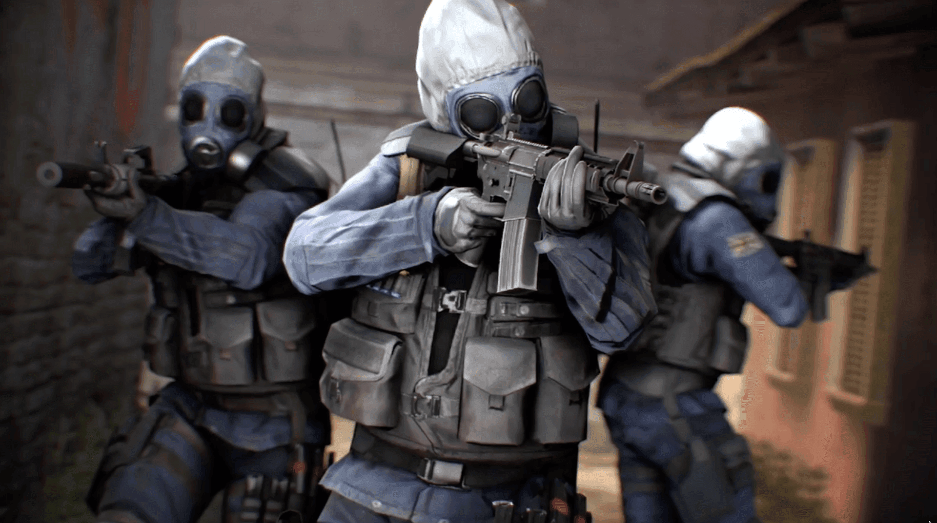 Three figures in blue uniforms and gas masks, armed with rifles, are shown in a tactical formation, suggesting a tense and action-oriented scenario. The central figure is prominently featured, aiming their weapon forward, while the others provide support from slightly behind. The overall mood is serious and focused, reminiscent of a scene from a video game or military simulation.