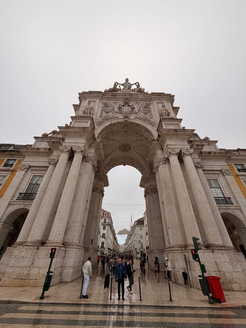 Standing tall and majestic, the Rua Augusta Arch in Lisbon welcomes visitors with its intricate details and grand presence. The arch, a symbol of the city's resilience and rebirth, frames a bustling street filled with people, hinting at the vibrant life within. The cloudy sky adds a touch of dramatic flair to this iconic landmark, making it a truly captivating sight.